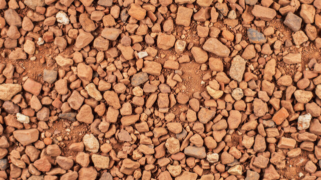Red gravel ground texture. Top view of crushed stone and pebbles for construction background.