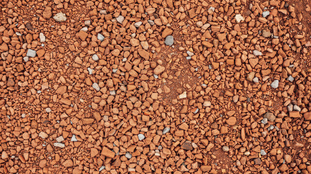 Red gravel ground texture. Overhead view of crushed stone surface for construction background.