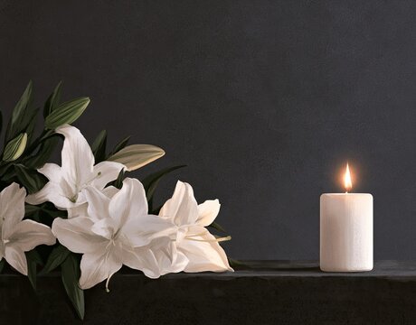 White lilies rest beside a glowing pillar candle against a dark, moody background
