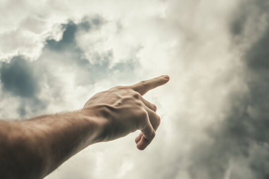 people of ai, hand with an outstretched pointing finger beneath storm clouds in a surreal perspective, photorealistic