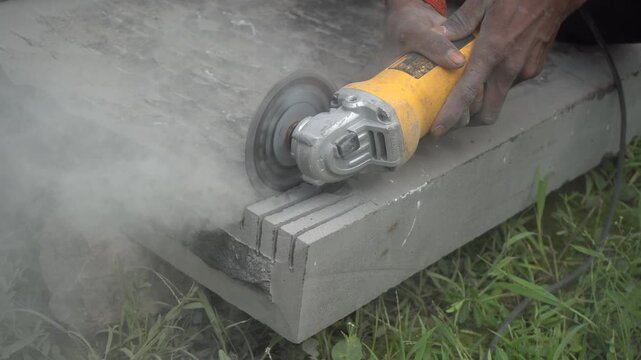 Industrial angle grinder cutting concrete slab, power tool masonry work with dust, professional construction worker grinding stone