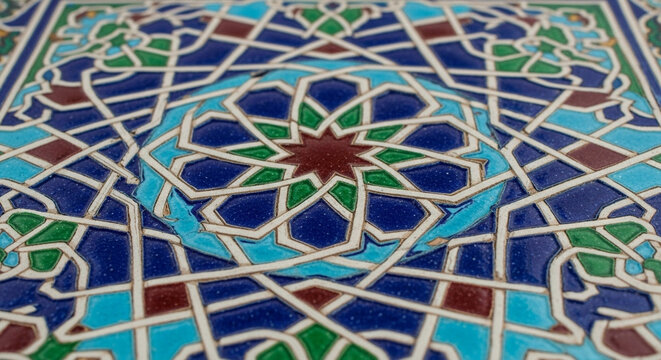 Intricate ceramic tile featuring vibrant geometric patterns with blue, green, and red hues reflecting traditional Middle Eastern artistry across the glazed surface for architectural projects