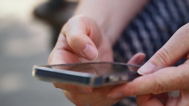 Close-up of hands operating a modern smartphone, with the user intentionally cropped from the frame. Digital communication, mobile applications, technology, connected lifestyle concept. 4K.