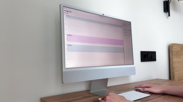 business schedule planning session on computer. Freelancer checks corporate timetable task logs using modern desktop monitor interface screen. Light cozy workspace background enhances remote