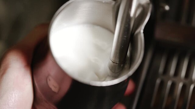 Barista Steaming Fresh Milk in Stainless Steel Pitcher for Smooth Specialty Coffee Preparation