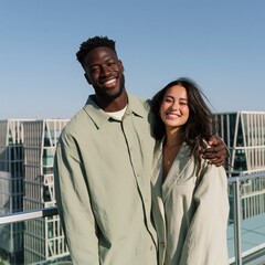 Naklejka premium Smiling multicultural couple on rooftop balcony with city skyline view for travel lifestyle wallpaper and relationship background
