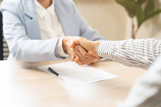 Close up successful job interview and recruitment concept with professional HR manager shaking hands with a selected candidate after a positive career hiring agreement in a bright modern office.