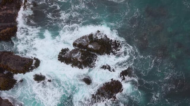 Waves roll in, hitting rocks near the shore in Mendocino, close to Fort Bragg, California on a clear day.