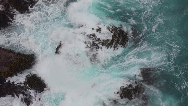 Ocean waves pass over rocks along the shoreline of Mendocino near Fort Bragg in California. The view captures the movement and energy.