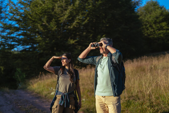 Couple exploring nature while hiking with binoculars