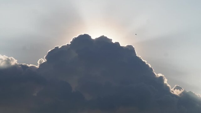 Dark cumulus cloud with glowing silver lining and sunlight behind