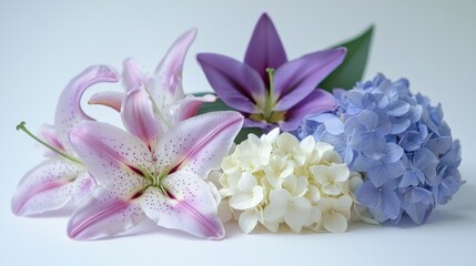 Obraz premium A stunning close-up of vibrant garden flowers like lilies, tulips, and hydrangeas, arranged delicately on a white surface.