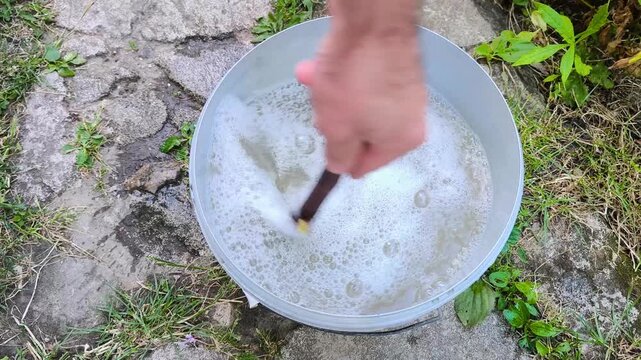 Preparing fungicide solution by mixing it with water in a bucket outdoors