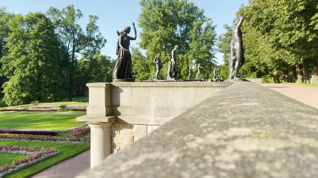Classical bronze statues stand proudly along a high stone terrace overlooking manicured gardens. The grand vista in Catherine Park, Saint Petersburg fills visitors with awe and peaceful joy.