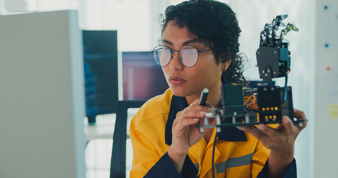 Young Black female engineer coding AI robot arm in modern laboratory. Robotics, artificial intelligence, technology, stem, future, innovation, diversity, automation, machine learning concept.