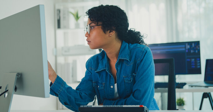 Young professional African American female programmer coding AI software on screens in modern home office. Generative AI, machine learning, digital innovation, future technology, online job concept.