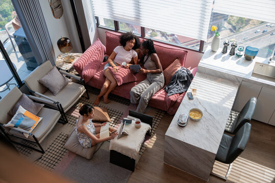 Two Women Sharing Tablet While Friend Studies at Home