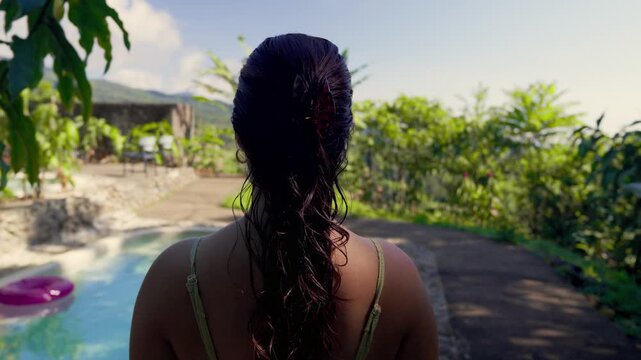 Individual with wet hair walking towards a swimming pool