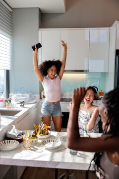 Friends joyfully celebrating together in a sunlit kitchen.