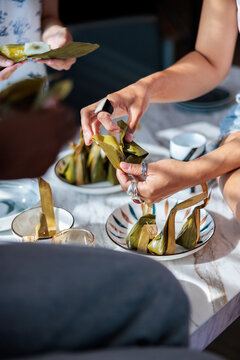 Friends sharing and unwrapping traditional leaf wrapped desserts.