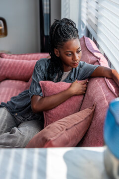 Woman Looking Out Window While Sitting on Sofa at Home