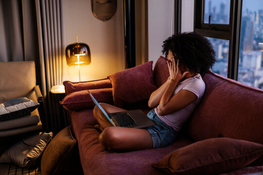 Woman Covering Face While Using Laptop at Night