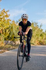 Naklejka premium Female Cyclist Riding Road Bike in Aerodynamic Position on Quiet Country Road During Training