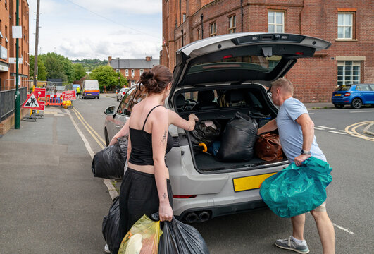 Gen Z girls loading their belongings into a car with one of their Dads