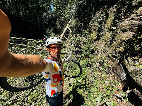 Cyclist Carrying Bicycle Through Fallen Trees