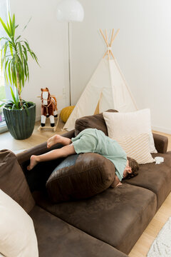 A toddler jumping on the sofa in the living room