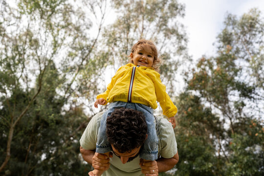 Happy Child Riding on Father&rsquo;s Shoulders Outdoors
