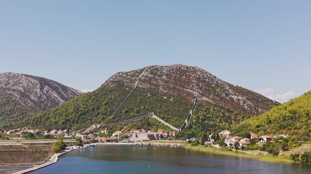 Panoramic view of Ston, Croatia, featuring historic fortress walls, Drums Tower, rugged mountains, traditional red-roofed houses, and the scenic Adriatic coast