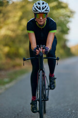 Naklejka premium Female Cyclist Training on Road Bike Wearing Helmet and Sunglasses During Outdoor Fitness Ride
