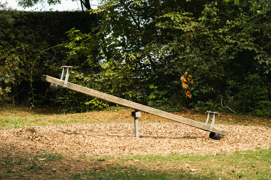 Wooden seesaw rests in leafy park