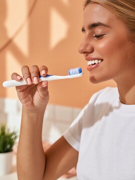 Happy young woman brushing teeth in white shirt and bathroom