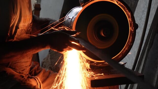 Person sharpening knife on grinding wheel with bright sparks