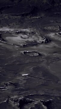 The view shows the uneven surface of a celestial body with deep craters and dark areas. This landscape features a mix of textures and shadows. The scene captures a sense of distance and scale.