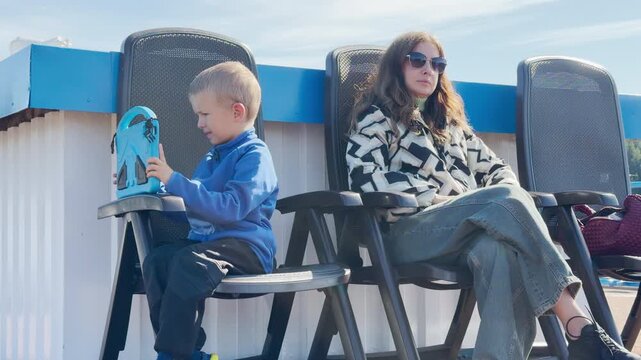 A happy mother and son relax comfortably on chairs aboard a cruise ship. They enjoy the peaceful journey along the Neva River. This lovely travel moment captures Saint Petersburg.
