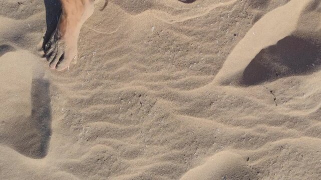 High angle view of sandy beach texture with footprints and natural wave ripples, peaceful summer coastal background for travel and environmental concept projects.