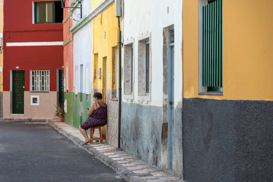 Woman sitting peacefully alone on a colorful quiet street.
