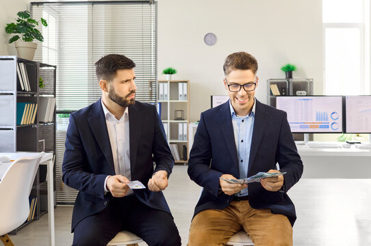 Employees workers compare salary wages in office disparity. One man gets a bonus while colleague counts more notes, exposing payroll inequality and compensation. Unfairness in pay gap clear.