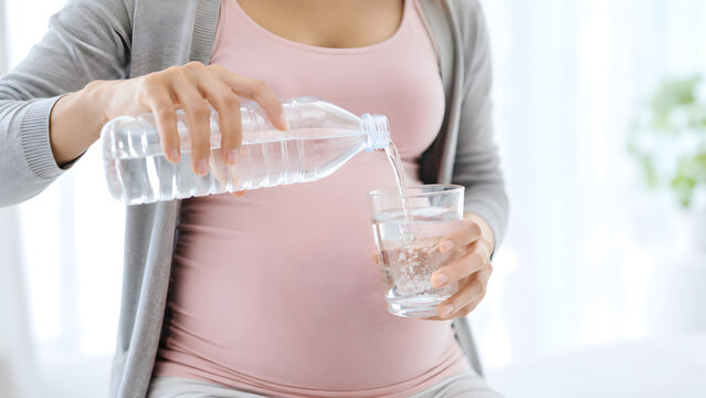 Pregnant woman drinking water from glass, representing healthy hydration during pregnancy, prenatal wellness, maternal care, nutrition, and healthy lifestyle