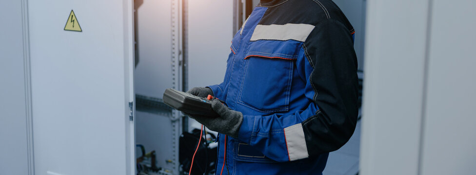 Electrician testing electrical cabinet with multimeter for maintenance background and technical manual banner design