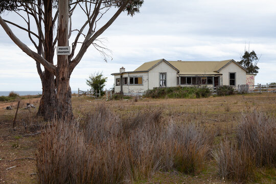Abandoned derelict wooden house on the east coast of Tasmania with private property sign