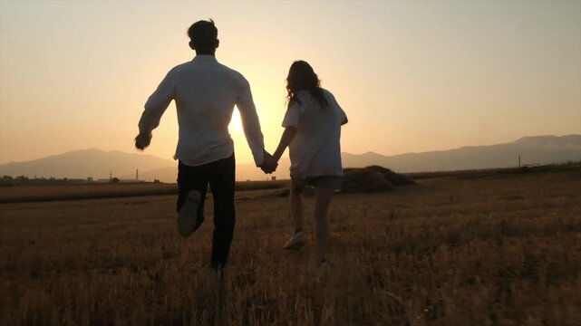 Happy young girl and boy running hand in hand toward the sunset, friendship and youth, optimism and new beginnings, enjoying life in the present moment, carefree outdoor lifestyle, slow motion