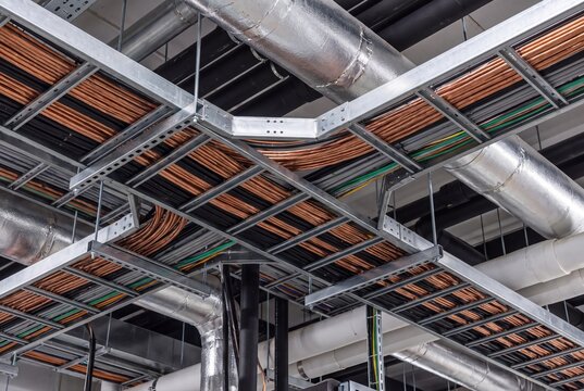 Industrial cable trays and piping system in modern factory ceiling