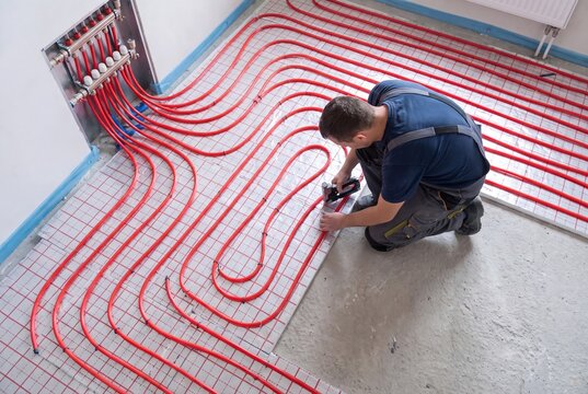 Underfloor heating installation worker mounting red pipe system