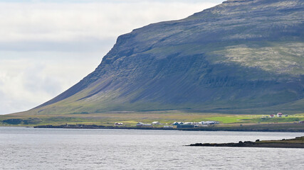Cinematic and peaceful view of massive mountains along the coast of the Westfjords in Iceland on a cloudy day, creating a dramatic and tranquil natural landscape. © Asanee