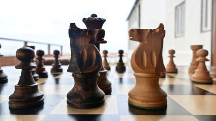 A traditional wooden chess game depicting a strategic confrontation between two opposing sides, symbolizing the struggle for territory, resources, political power, tactical planning, and dominance. © Asanee