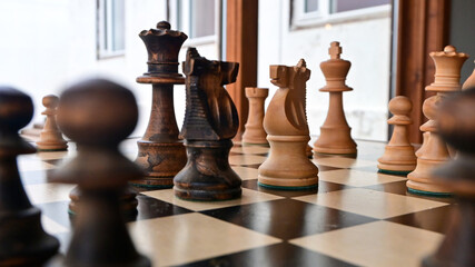 A traditional wooden chess game depicting a strategic confrontation between two opposing sides, symbolizing the struggle for territory, resources, political power, tactical planning, and dominance. © Asanee
